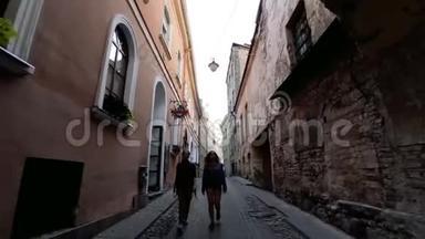 沿着欧洲城市的古老街道行走。 两个年轻的女人走在维尔纽斯老城狭窄的街道上。 二.
